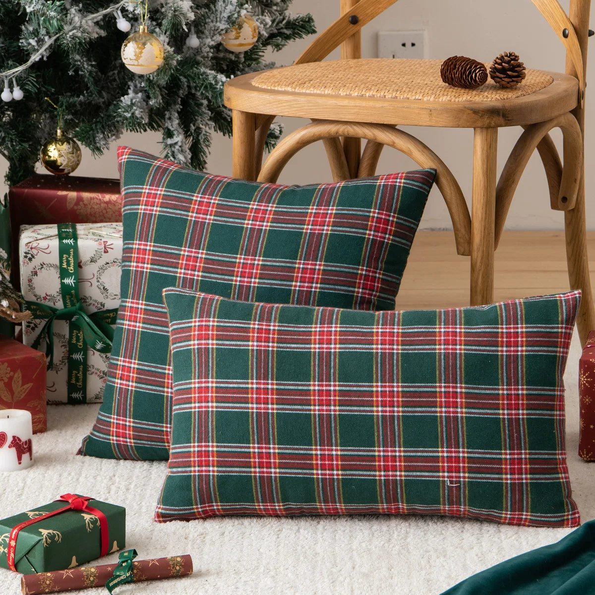 A set of two green and red tartan plaid decorative throw pillow covers resting on a white rug.