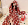 A young woman wearing a red and brown plaid flannel kimono robe indoors.