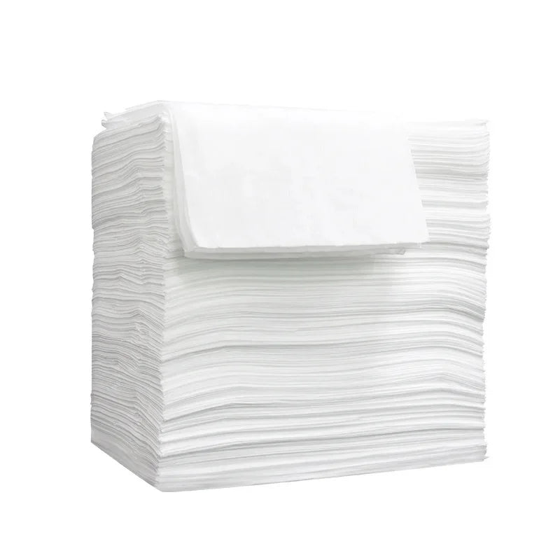 A stack of white disposable non-woven beauty and salon sheets.