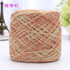 A ball of metallic silk crocheting and knitting yarn with a pinkish-gold color and woven texture.