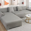 A modern gray velvet sofa cover for an L-shaped sectional with matching pillows and decor.