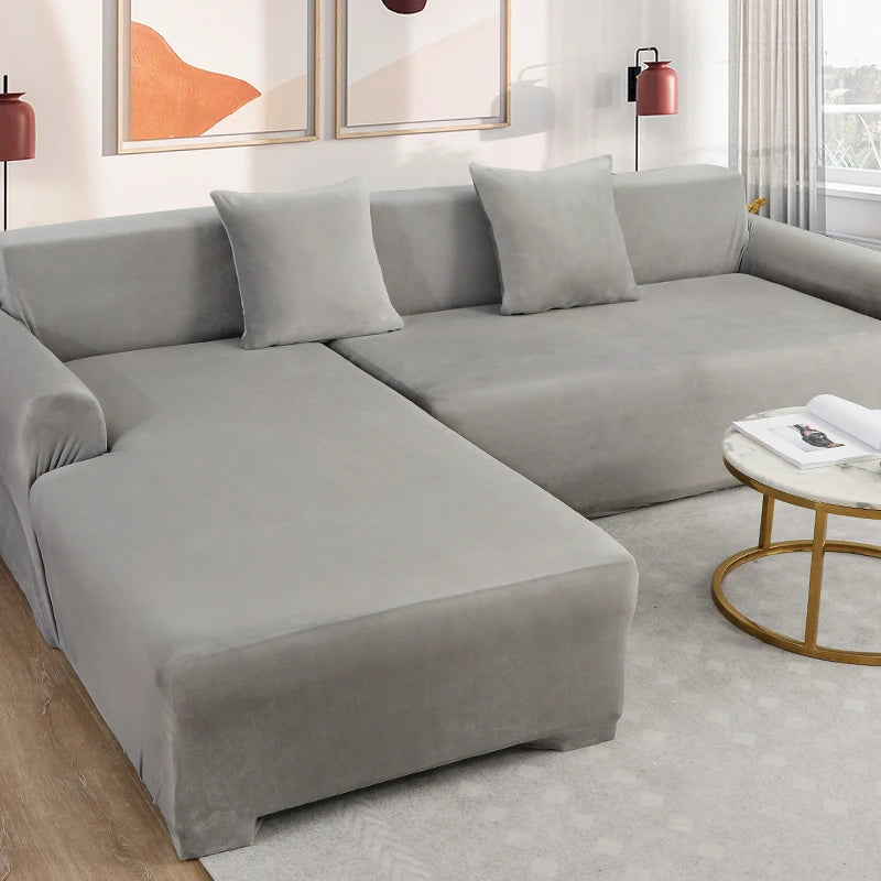 A modern gray velvet sofa cover for an L-shaped sectional with matching pillows and decor.