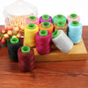 A collection of 24 spools of colored sewing threads in various shades and thicknesses arranged on a wooden board.