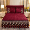 A deep red velvet bed skirt with intricate embroidery and scalloped hem, displayed on a bed.