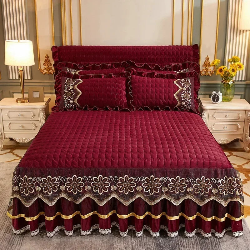 A deep red velvet bed skirt with intricate embroidery and scalloped hem, displayed on a bed.