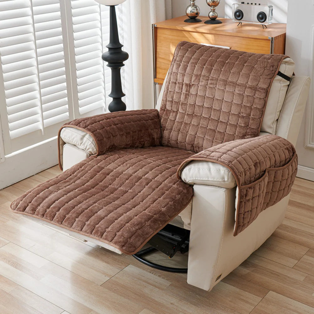 A tan quilted stretch recliner cover with storage pockets resting on a light wood floor.