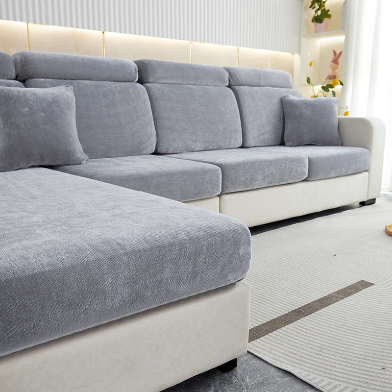 A modern gray stretchable chenille sofa cushion cover on a light-colored sectional sofa with a white base.