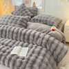 A gray plush rabbit hair bedding set featuring soft pillows and a textured blanket.