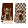 A set of two brown plaid kitchen towels featuring a Highland calf head with flowers.
