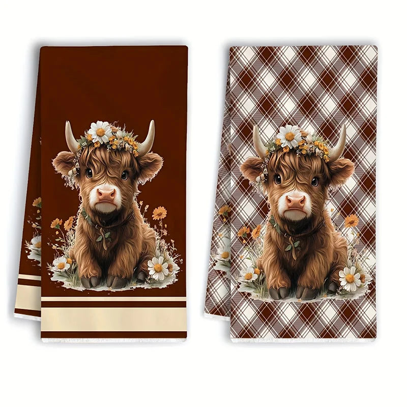 A set of two brown plaid kitchen towels featuring a Highland calf head with flowers.