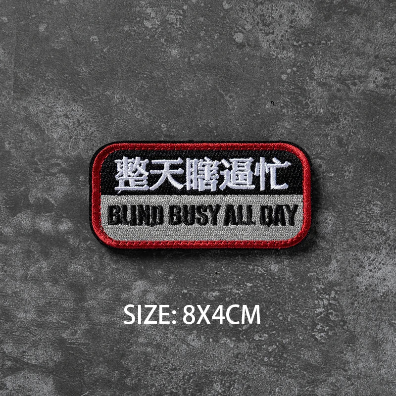 A black embroidered badge with white text reading Blind Busy All Day on a dark gray textured background.