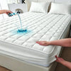 A hand is pouring water onto a white quilted mattress protector, demonstrating its waterproof feature.