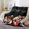 A black fleece throw blanket featuring a group of seven members of Stray Kids in a stylized design.