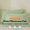 A pair of plain light green pillowcases with a simple texture and cloud-like comfort.