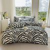 A black and white zebra print duvet cover set with pillows displayed on a bed in a bright room.