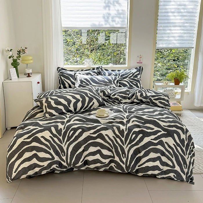 A black and white zebra print duvet cover set with pillows displayed on a bed in a bright room.