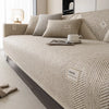 A beige linen sofa cover cushion with textured fabric and small labels is displayed on a bed.