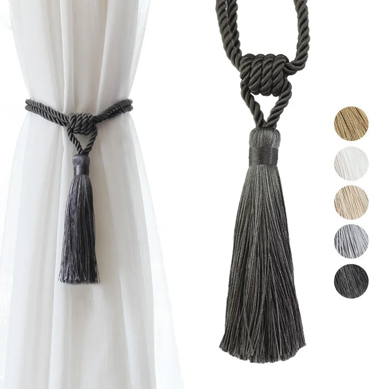 Elegant black curtain tiebacks with long gray tassels hanging from a rope