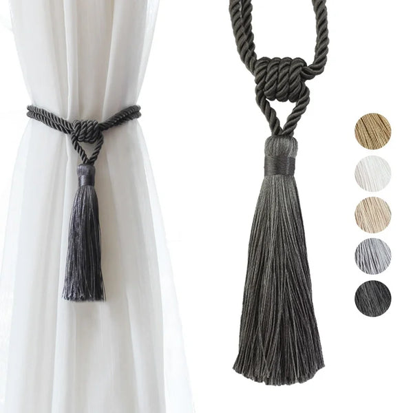 Elegant black curtain tiebacks with long gray tassels hanging from a rope