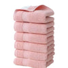 A stack of six pink, textured face towels made of premium pure cotton.