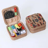 A light brown storage box containing various sewing needles and tools, including a red ruler.