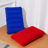 A blue inflatable travel pillow and a red inflatable travel pillow resting on a wooden surface.
