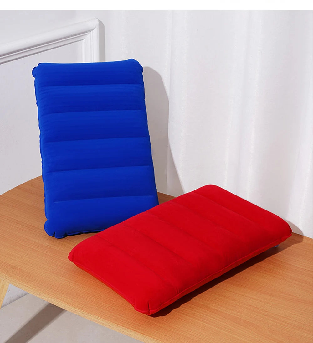 A blue inflatable travel pillow and a red inflatable travel pillow resting on a wooden surface.