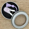 Mini precision sewing scissors with a lavender protective cover and purple thread on a wooden surface
