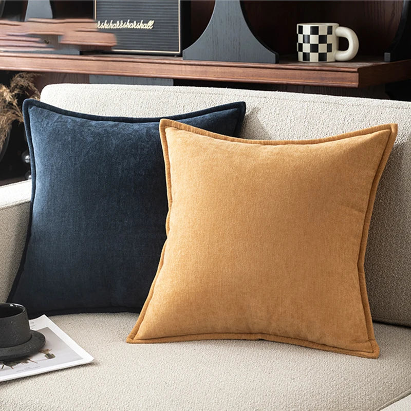 A close-up of a mustard yellow chenille throw pillow resting on a light beige sofa.
