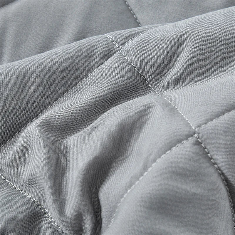 Gray quilted fabric showing stitching detail on a bedspread.