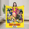A yellow throw blanket featuring characters from The Bob's Burgers movie, including Tina Belcher and Gene Belcher.
