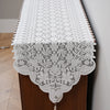 White embroidered lace table runner displayed on a wooden cabinet.