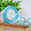 Roll of light blue satin ribbon with a white core displayed on a wooden board.