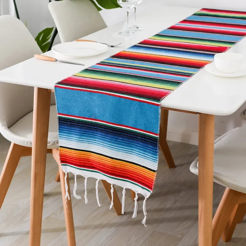 Colorful cotton Mexican serape table runner with stripes displayed on a white table.