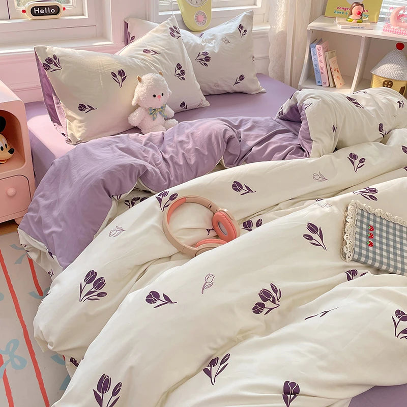 A white and purple duvet cover set with matching pillowcases and a small stuffed animal on a bed.