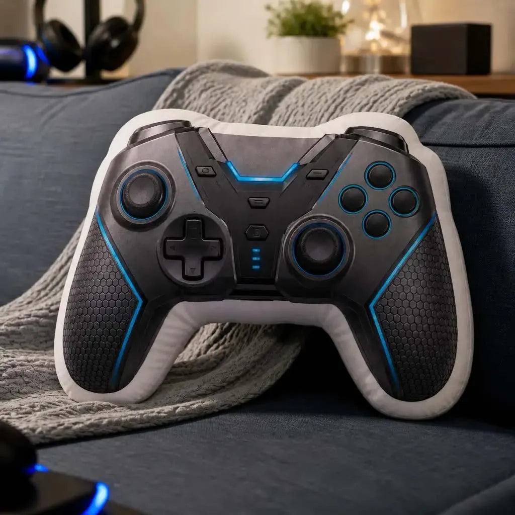 A black and white gamer controller plush resting on a gray blanket on a blue sofa.