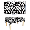 Black and white cow print disposable plastic tablecloth displayed on a wooden table.