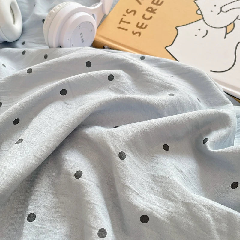 A light gray microfiber duvet cover is draped on a surface, featuring small dark polka dots.
