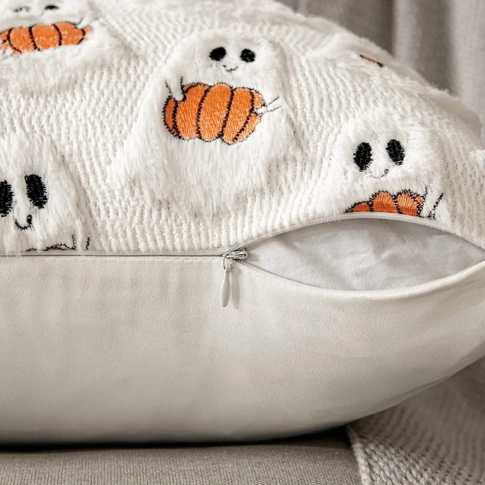 A white knitted throw pillow cover decorated with orange pumpkin and ghost patterns.