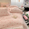 A pink and white gingham duvet cover set with floral bowknot accents displayed on a bed.