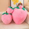 Pink plush strawberry throw pillow with green leaves and a brown stem