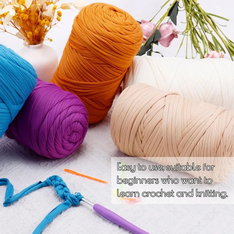 A collection of thick orange, purple, and beige yarn skeins with crochet and knitting needles visible.