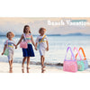 Three children walking on the beach with colorful mesh bags.