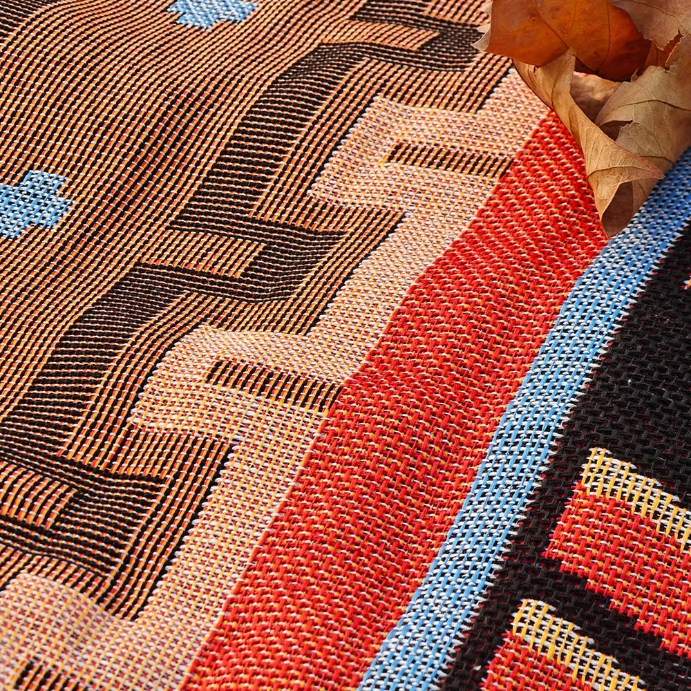 Close-up of a woven blanket featuring geometric patterns in brown, red, and blue tones.