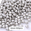 A pile of silver-toned geometric acrylic beads for jewelry making