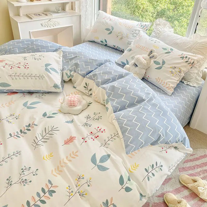 A light blue and white floral bedding set featuring various patterned pillows and a duvet on a bed.