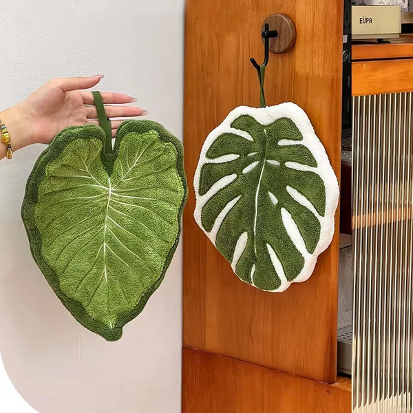A green leaf-shaped absorbent microfiber towel hanging on a wooden door.