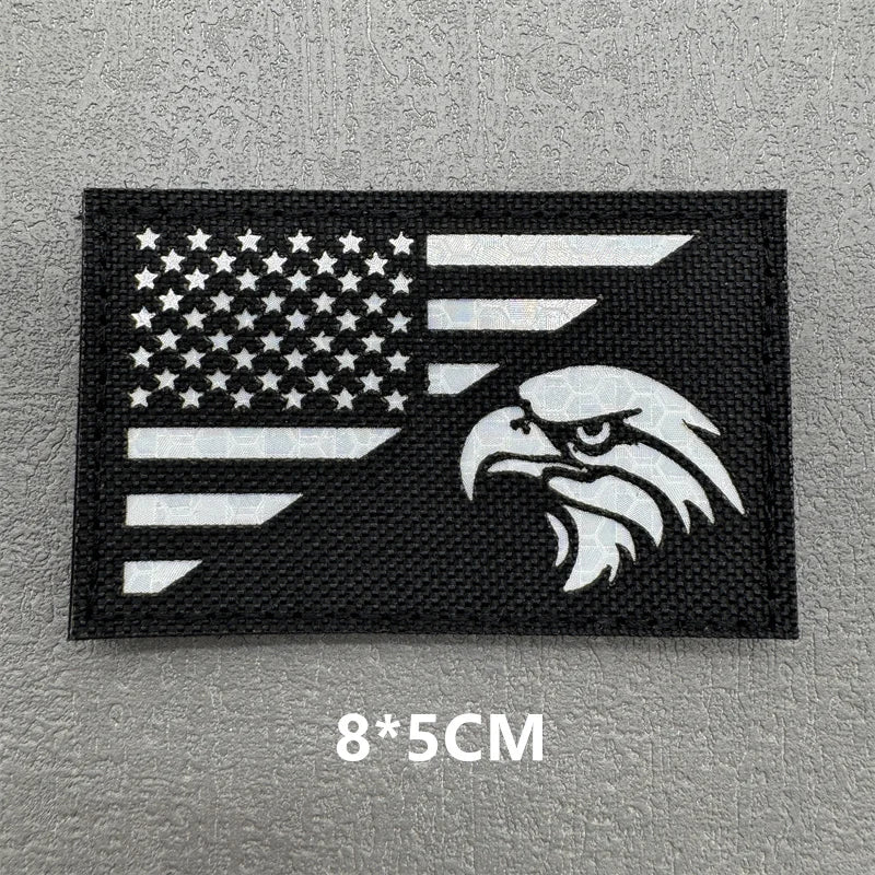 Black embroidered patch featuring a white American flag and an eagle silhouette on a gray background.