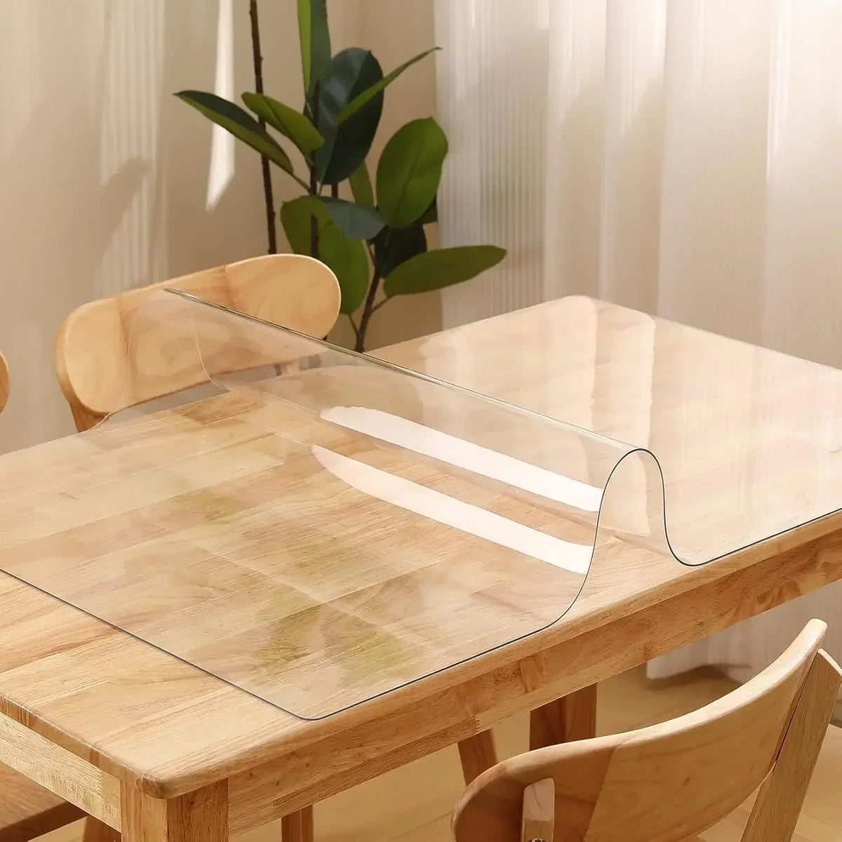 A clear PVC table protector mat is placed on a light wood table.