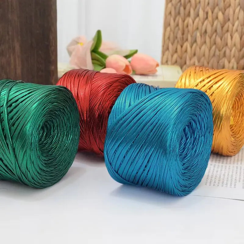 A collection of metallic cake colored yarn spools in green, red, blue, and gold.